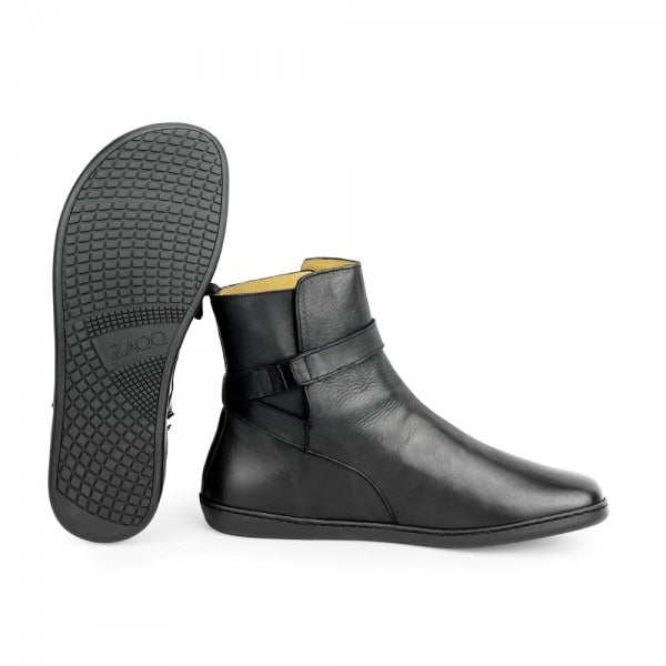 A photo of Zaqq Riquet boots made from Nappa leather and rubber soles. The boots are black in color and a pull up style with a decorative buckle around the ankle. Both boots are shown one boot is shown from the right side and the other boot is shown behind facing upright to show the sole against a white background. #color_black
