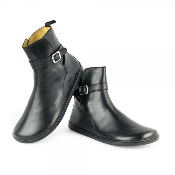 A photo of Zaqq Riquet boots made from Nappa leather and rubber soles. The boots are black in color and a pull up style with a decorative buckle around the ankle. Both boots are shown the right boot is shown from the right and the left boot is facing downward with its heel resting on the right boot against a white background. #color_black