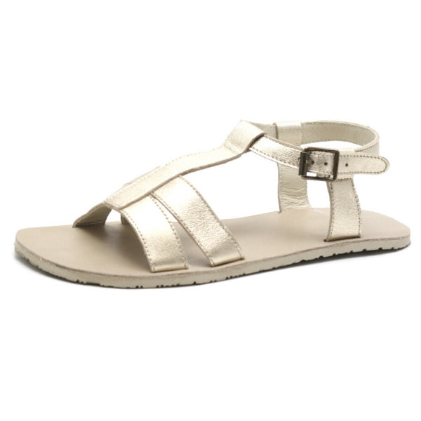 A photo of Zeezoo Freya Gold sandals made with leather and light beige leather topped rubber soles. The sandal straps are shiny they have double straps in the front, a single strap running up the middle of the foot,  around the ankle and heel with a small buckle. One sandal is shown from the left side against a white background in this photo. #color_gold