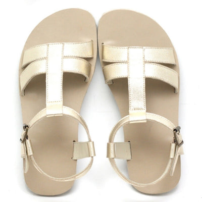 A photo of Zeezoo Freya Gold sandals made with leather and light beige leather topped rubber soles. The sandal straps are shiny they have double straps in the front, a single strap running up the middle of the foot,  around the ankle and heel with a small buckle. Both sandals are shown from the top down against a white background in this photo. #color_gold