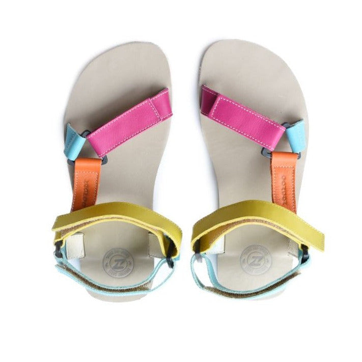 A photo of Zeezoo Olymp Rainbow sandals made from leather with velcro and a light beige leather topped rubber soles. The sandal straps are pink, light blue, orange, and yellow. The straps cross the front of the foot and a single strap runs along the outside of the top of the foot and around the ankle and heel. Both sandals are shown from the top down against a white background. #color_rainbow-olymp