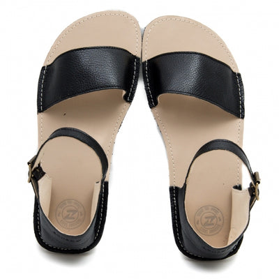 A photo of Zeezoo Siren Black Sandals made of leather and a light beige leather topped black rubber sole. The sandals have a front foot crossing strap, a leather ankle strap and heel cup. Both sandals are shown from the top down against a white background. #color_black